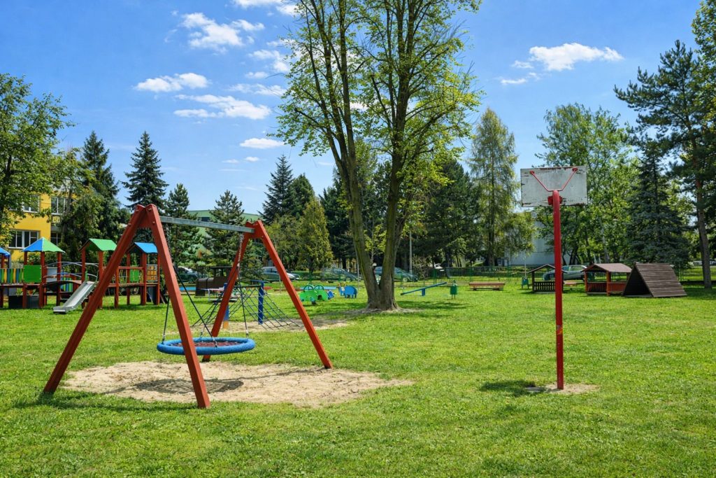 Plac zabaw z trawiastą nawierzchnią i instalacjami do zabawy dla dzieci.